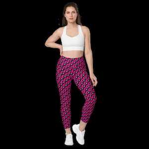 May include: Pink leggings with a black and white geometric pattern. The leggings are cropped and have a high waist.