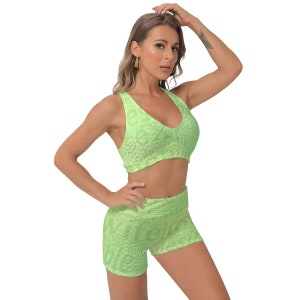 Puede incluir: Un conjunto deportivo de dos piezas en color verde brillante con un patrón texturizado. La parte superior es un sujetador deportivo con cuello redondo y estilo de espalda de nadador. Los pantalones cortos son de cintura alta y tienen una cintura ancha.