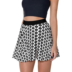 May include: A black and white skater skirt with a repeating spade pattern. The skirt has a black waistband and a flared shape. The design is a striking, graphic print, suitable for casual wear.