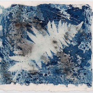 May include: Abstract cyanotype print featuring a central white fern-like shape against a textured background of deep blue and gray hues. The edges of the paper are rough and uneven, adding to the artwork's unique aesthetic. The print has a vintage, handmade feel.