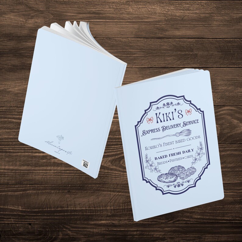 May include: Two light blue notebooks with a vintage design. The front cover of one notebook features a logo with the text "Kiki's Express Delivery Service" and the text "Koriro's Finest Baked Goods Baked Fresh Daily Breads, Pastries, Cakes".