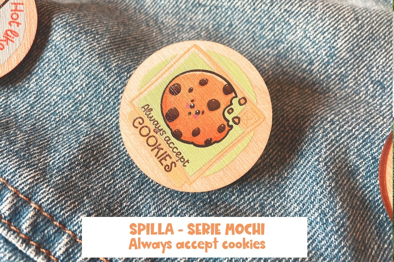 Op de afbeelding: Een ronde houten pin met een cartoon-koekje erop. Het koekje heeft chocolade chips en een hap eruit. De tekst "Always accept COOKIES" staat op de pin.