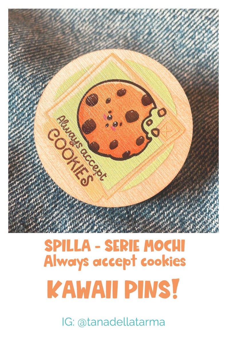 Op de afbeelding: Een ronde houten pin met een cartoon-koekontwerp. De koek heeft chocolade-chips en een groene frosting-beet. De tekst "Always accept cookies" staat rond de koek. De pin is op een blauwe denim-achtergrond.