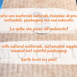 Op de afbeelding: Een close-up van een bruine papieren zak met de tekst "Realizzata con materiali naturali, tecniche di produzione sostenibili, packaging eco ma colorato: Tana della FARM La spilla che piace all'ambiente!" en "Made with natural materials, sustainable supplier and minimal but colorful packaging: Earth loves my pins!"