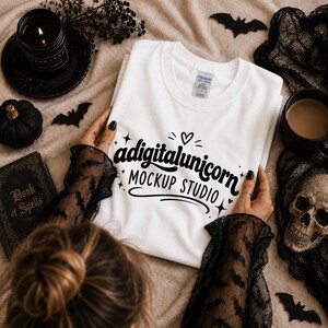 May include: A white short-sleeved t-shirt with a black graphic print that reads adigitalunicorn MOCKUP STUDIO, featuring a small heart and star accents. The shirt has a Gildan brand label on the inside of the collar.
