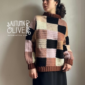 Puede incluir: Un suéter de crochet patchwork en una variedad de colores que incluyen negro, marrón, rosa y crema. El suéter tiene un cuello alto y mangas largas. El texto "AUTUMN OLIVE Crochet" está en el lado izquierdo de la imagen.