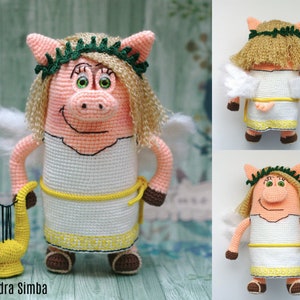 May include: A handcrafted crochet pig doll, featuring angel wings, a green laurel wreath, and blonde hair. The pig is dressed in a white dress with yellow detailing and holds a yellow lyre. A charming, whimsical handmade item.