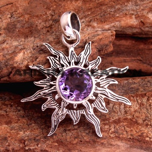 May include: A silver pendant featuring a sunburst design with a large amethyst gemstone in the centre.