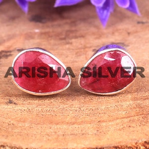 Könnte beinhalten: Ein Paar silberne Ohrringe mit roten Edelstein-Tropfen.