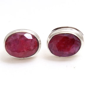 Puede incluir: Un par de pendientes de plata con piedras preciosas de rubí rojo de forma ovalada.