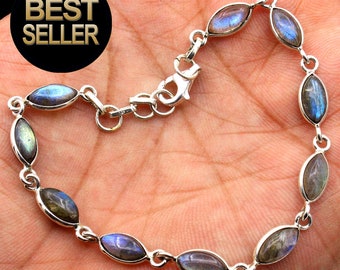 Può includere: Un braccialetto d'argento con chiusura a moschettone presenta pietre preziose di labradorite di forma ovale con sfumature iridescenti blu, verdi e dorate.