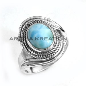 Peut inclure: Une bague en argent avec une pierre ovale bleu et blanc sertie dans une bande d'argent décorative.