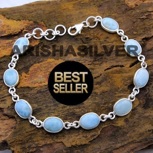 May include: A silver chain bracelet with oval-shaped blue gemstones. The bracelet has a lobster claw clasp.