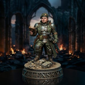 May include: A miniature figurine of a soldier wearing a green beret, olive drab military coat, and metallic armour plating. The figure holds a small book and a weapon, standing on a circular base with the name ZELENSKYY embossed on the front.