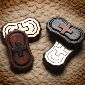 May include: Four wooden and metal tokens with a cross design. The tokens are in shades of brown, black, and silver.