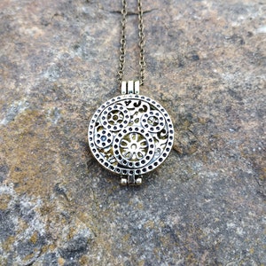 May include: A gold-toned necklace with a round, filigree pendant. The pendant has a delicate, intricate design with a circular pattern.