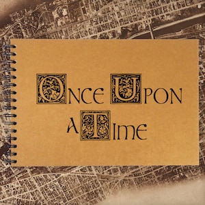 May include: A brown notebook with a spiral binding and the words "Once Upon A Time" written in black lettering with decorative flourishes.