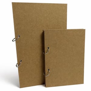 May include: Two brown cardboard binders with silver metal ring binders. The larger binder is leaning against the smaller one. The binders are made of a thick, sturdy material, and are suitable for organizing documents.