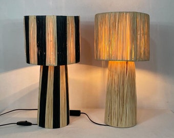 Può includere: Due lampade da tavolo con paralumi intrecciati. La lampada a sinistra ha strisce intrecciate nere e naturali. La lampada a destra ha un paralume intrecciato naturale.