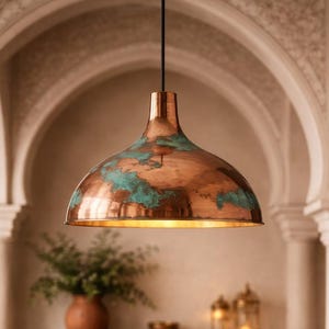 May include: A copper pendant light with a dome-shaped shade, showing a verdigris patina. The light hangs from a black cord, illuminating a warm interior space. The design is reminiscent of Moroccan or bohemian decor.