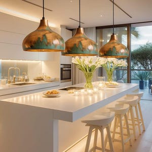 Könnte beinhalten: Eine moderne Küche mit einer weißen Insel und drei Kupfer-Pendelleuchten. Weiße Hocker sind an der Insel aufgereiht. Die Küche verfügt über weiße Schränke, ein Waschbecken und einen Blick nach draußen.