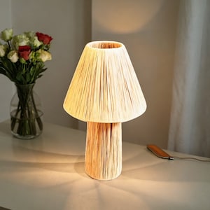 May include: A beige table lamp shaped like a mushroom with a woven shade and base.