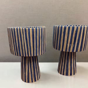 Può includere: Due vasi in ceramica a strisce blu e marroni con una parte superiore larga e rotonda e una base stretta e rotonda.