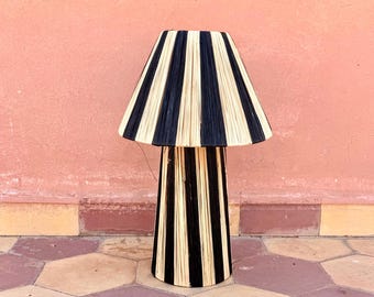 May include: A black and natural woven lamp with a wide, cone-shaped shade. The lamp is sitting on a tiled floor.