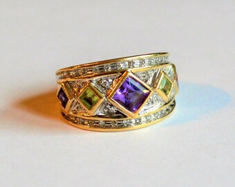 May include: A gold ring with a band of small diamonds and a row of colorful gemstones, including amethyst, peridot, and green tourmaline.