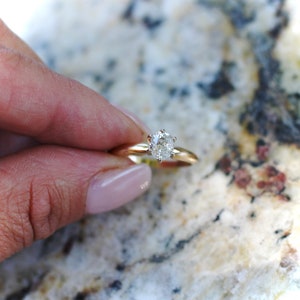 May include: A gold engagement ring with a round, clear diamond.