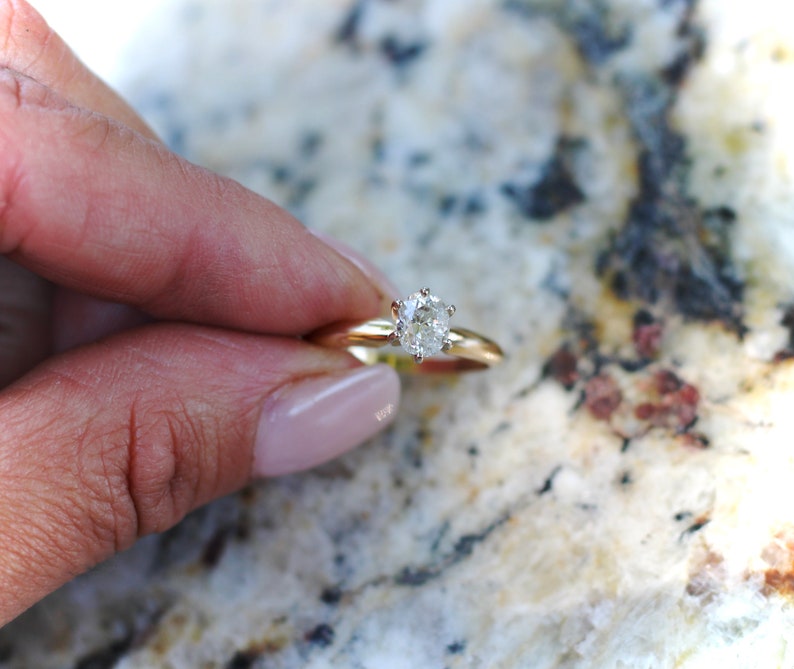 May include: A gold engagement ring with a round, clear diamond.