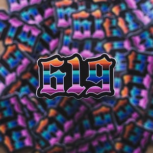 May include: A close-up of a sticker with the number "619" in a bold, black font. The numbers are outlined in white and filled with a rainbow stripe pattern.