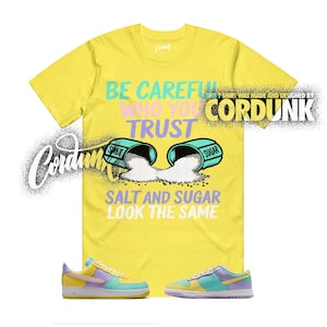 May include: A white ceramic mug with a black handle and the text "But First, Coffee" in a black, handwritten-style font. The mug is on a white surface.