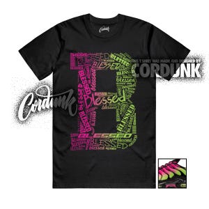 May include: Black t-shirt with a large "B" design composed of the word "Blessed" in pink and green. The shirt also features the text "THIS T SHIRT WAS MADE AND DESIGNED BY CORDUNK".