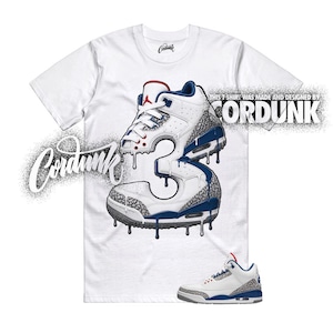 May include: A white short-sleeve t-shirt featuring a graphic of a sneaker shaped like the number 3 with blue and grey elephant print accents. The text Cordunk is printed in a stylized font, and the text THIS T SHIRT WAS MADE AND DESIGNED BY CORDUNK.