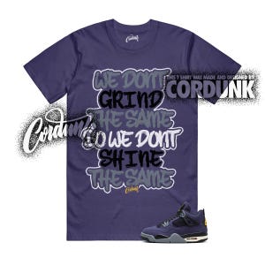 May include: A purple t-shirt with the text "WE DON'T GRIND THE SAME, WE DON'T SHINE THE SAME" in a graffiti-style design. A pair of purple and black sneakers is at the bottom. The shirt has a crew neck.