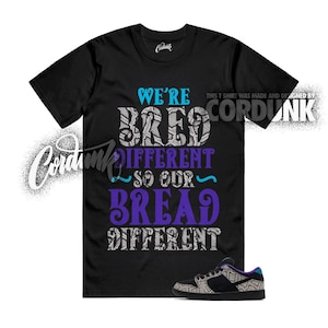 May include: Black t-shirt with the text "WE'RE BRED DIFFERENT SO OUR BREAD DIFFERENT" in blue and purple. A pair of black and gray sneakers with a patterned design is at the bottom. The shirt was made and designed by Cordunk.