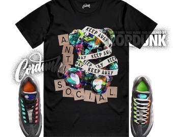 Peut inclure: T-shirt noir avec un ours coloré enveloppé d'un ruban "Keep Away". Le mot "ANTISOCIAL" est épelé avec des tuiles de Scrabble. Deux baskets aux accents colorés sont de chaque côté.