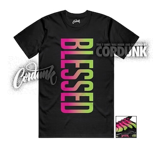 May include: Black t-shirt with the word "BLESSED" in a vertical gradient of pink and green. The shirt also features the text "THIS T SHIRT WAS MADE AND DESIGNED BY CORDUNK" and a small graphic of a shoe.