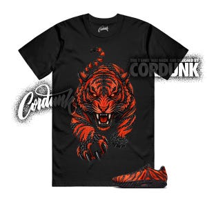 May include: A black short-sleeve t-shirt featuring a large, detailed graphic of a snarling tiger with orange and black fur. The text "CORDUNK" appears in white on the chest and upper right. A matching black and orange tiger-striped sneaker is shown.