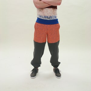 A pair of grey joggers with orange lace panels and an elasticated sports waistband. Size Medium