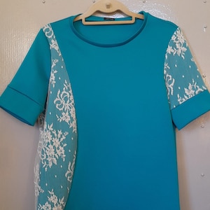 A turquoise t-shirt with lace overlay panels. Size Medium