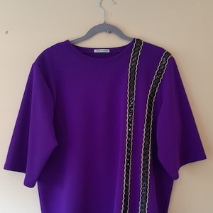 A purple stretch crepe t-shirt, with black and gold sequin trim details, size L/XL