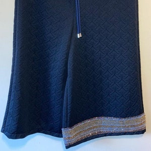 A pair of print embossed black shorts, with hand embellishment to 1 leg, and elasticated sports waistband, size Small.