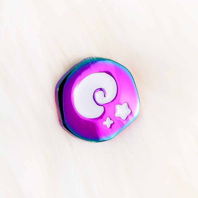 May include: A iridescent purple, blue, and green enamel pin with a white crescent moon and stars design.