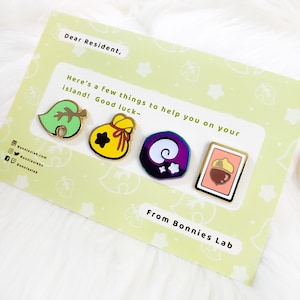 May include: A set of four gold-colored enamel pins featuring characters from the Animal Crossing video game series. The pins are on a card with the text "Dear Resident, Here's a few things to help you on your island! Good luck- From Bonnies Lab".