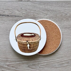 May include: A white ceramic coaster with a brown wicker basket with a handle and a white lid. The coaster has a cork backing.