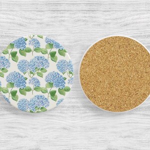 May include: Two round coasters, one with a blue and green floral pattern of hydrangeas and the other with a cork surface.