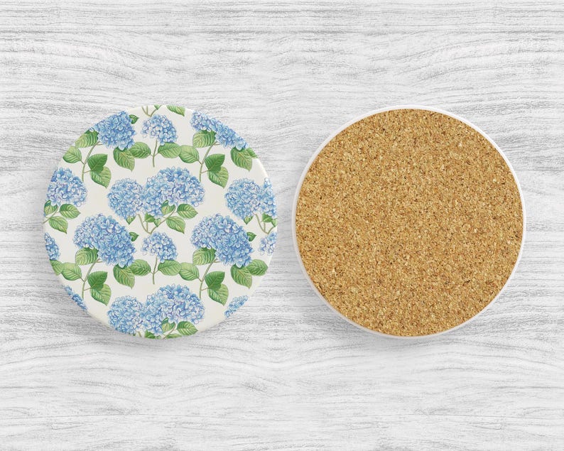 May include: Two round coasters, one with a blue and green floral pattern of hydrangeas and the other with a cork surface.