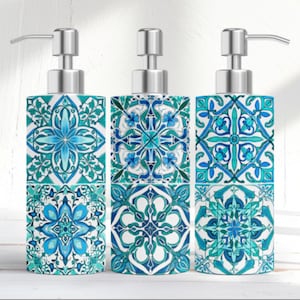 May include: Three decorative soap dispensers with silver pumps. Each dispenser features a repeating tile pattern in shades of blue and teal on a white background. The dispensers are square and have a modern design.